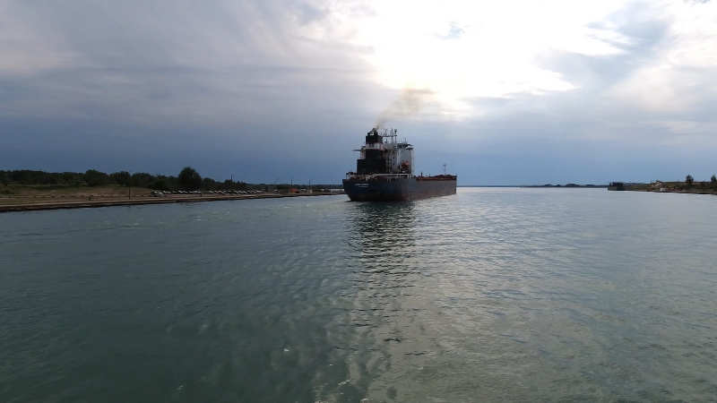 A Ship Passing Through the Soo Locks with Calm Waters and A Cloudy Sky in The Background