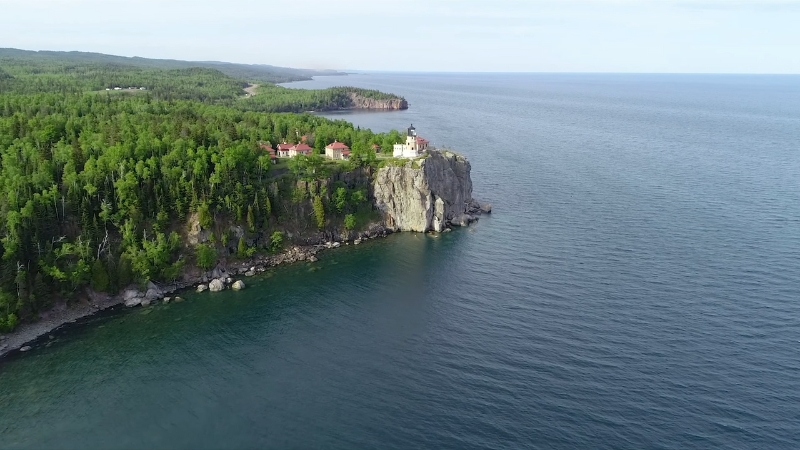 A lighthouse perched on a cliff overlooking the calm waters of Lake Michigan