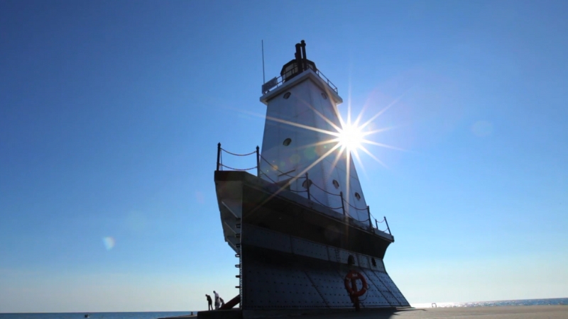 A lighthouse silhouetted by the sun over lake Michigan